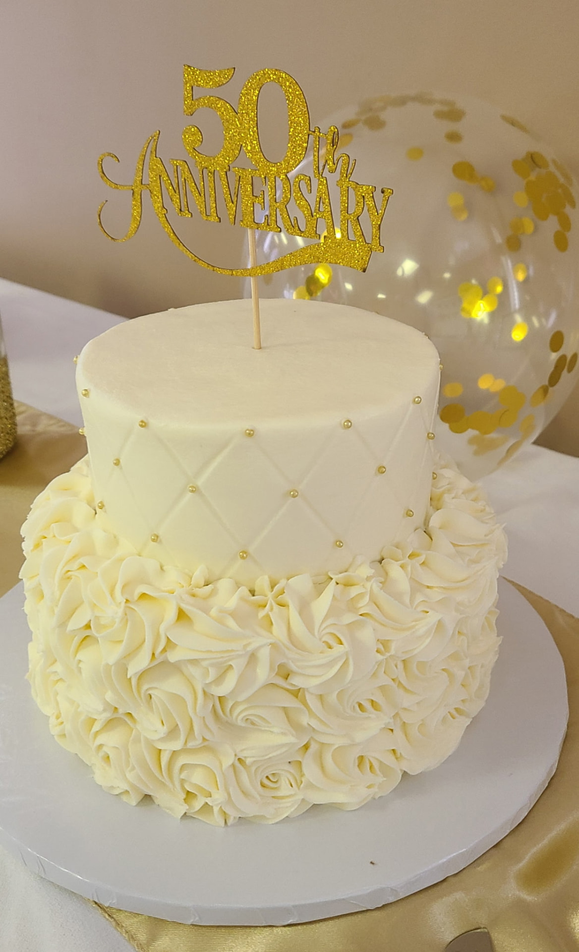 A gold 50th anniversary cake topper on a white celebration cake