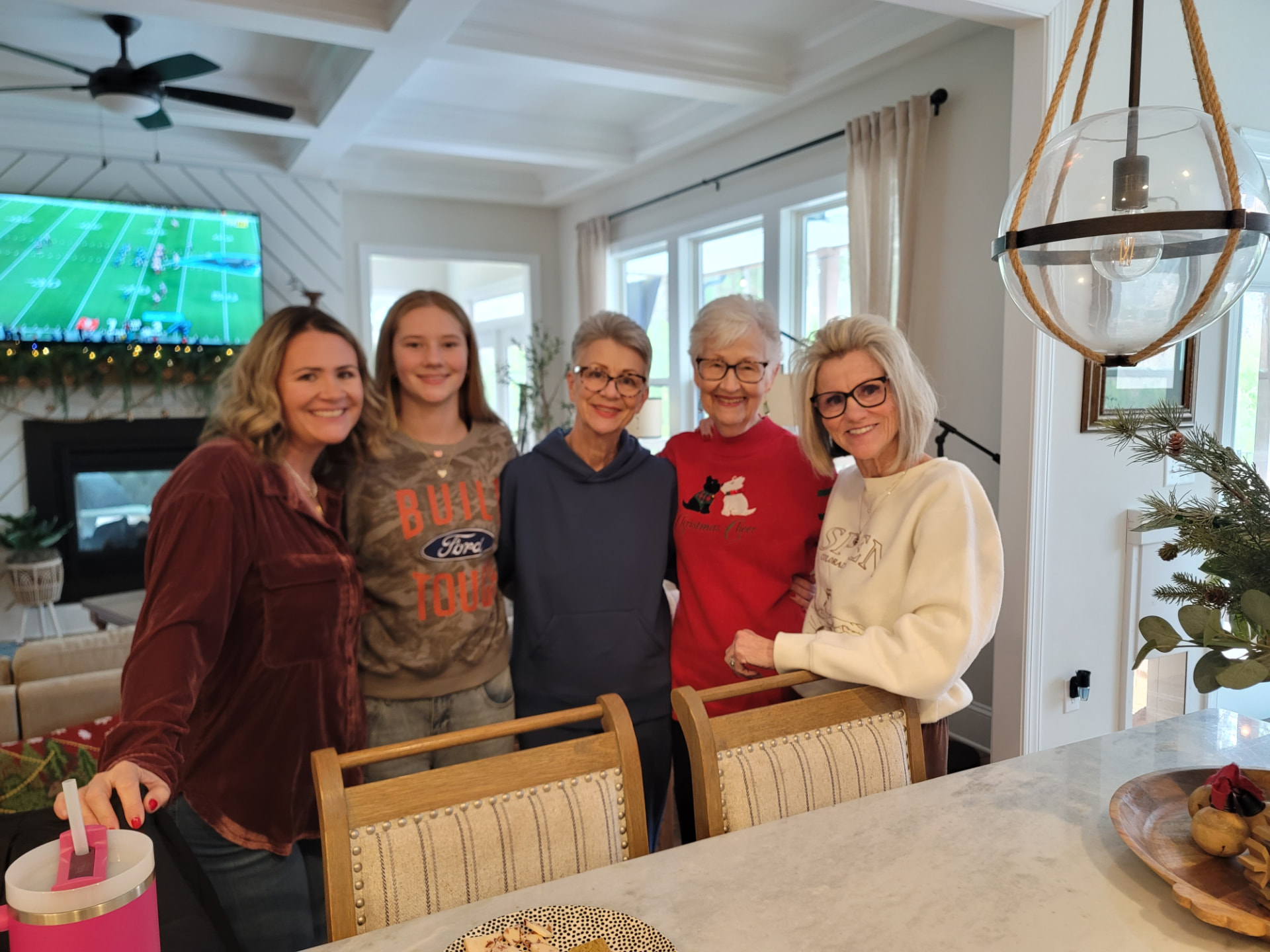 Three generations of women gathered together in a kitchen, smiling